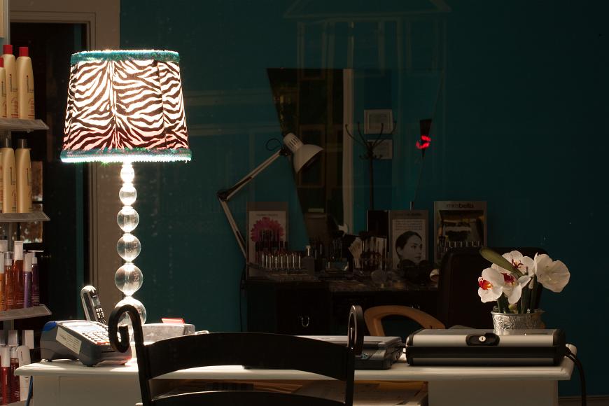 Night scene from a hairdressers salon in Kittery Maine A zebra print lamp with clear lucite stacked balls as the base illuminating a hairdressers salon at night in Kittery. A phone is on the table as well as fake...