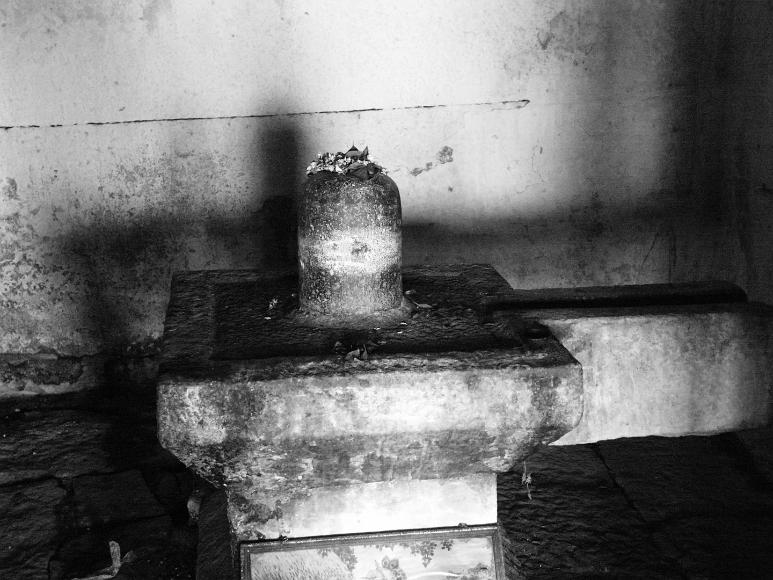 Lingam with flowers anointing it in a small shrine near Hampi Black and White image of a stone lingam, a symbolic penile representation, set within a yoni, a symbloic vaginal representation, is shown anointed with flowers...