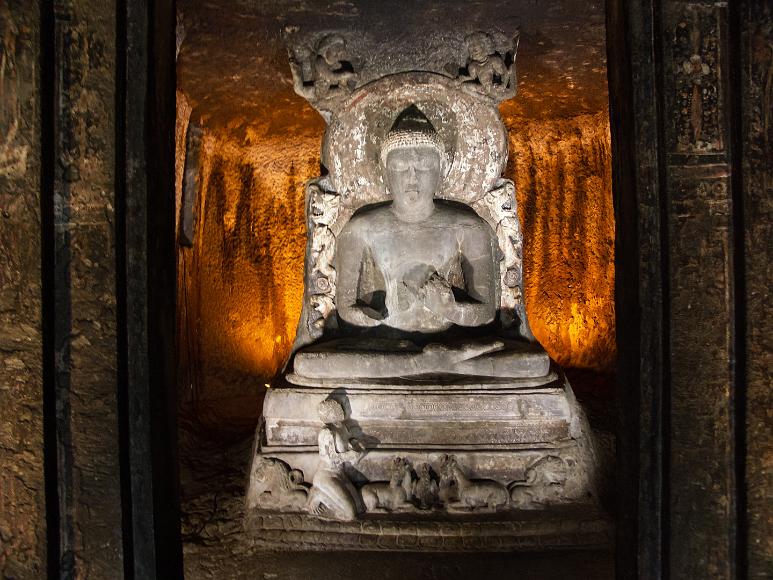 Sitting Buddha carved from stone at Ajanta Caves Cave one of the Ajanta caves, lit from behind and showing the sitting buddha in the dharmachakrapravartana mudra pose, carved into a rock cliffside in the...