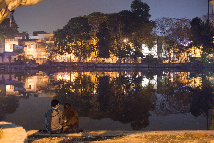 _DSC1107 A couple sits in fron of a water tank that reflects trees and lights at Layalka Mat, Kolkata, India