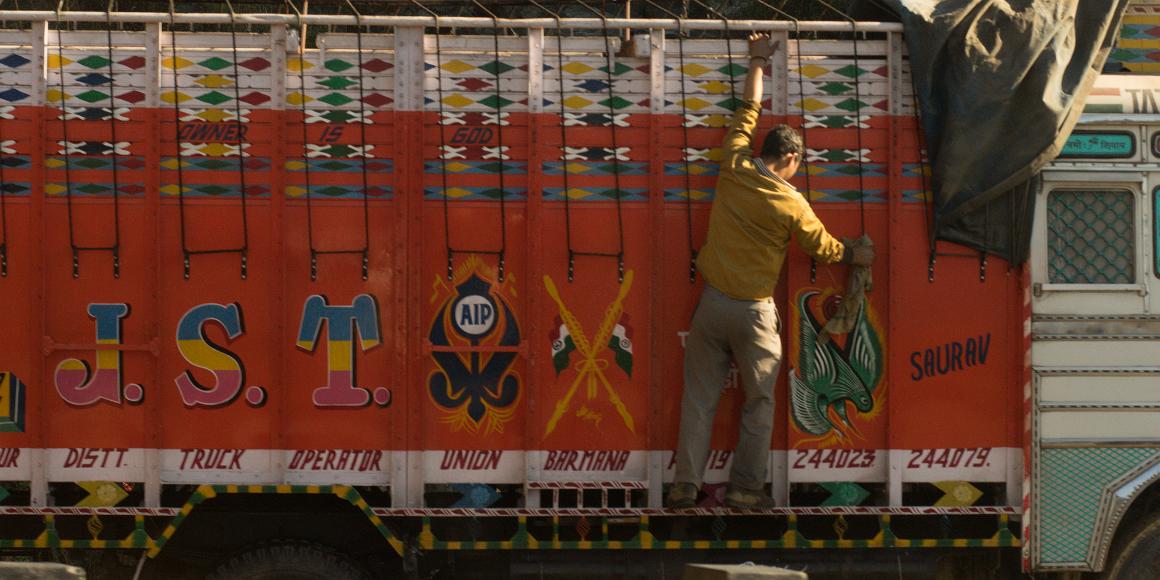 Keeping it clean Man climbs up onto truck that he is washing in India