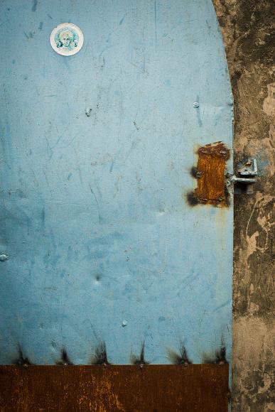 Blue door with rust and sticker in the rock garden of nek chand in Chandigarh, Haryana