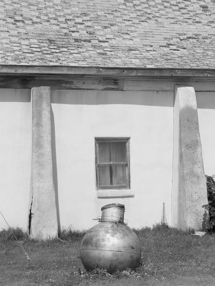 Old building and round gas tank Black and white photograph by Rana Banerjee of a, Nicodemus, Kansas