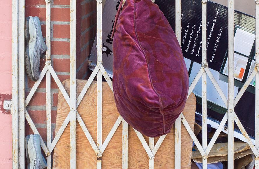 Closeup of a Chinatown street scene A pillow and a pair of shoes are stuffed into the front gate of a house that has junk behind it