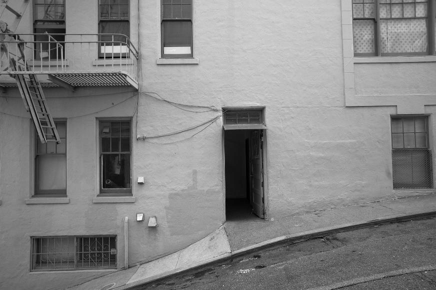 Chinatown Streets A very sharpley angled street with an open door in the center and many rectangular windows in a Chinatown back alley in San Francisco California