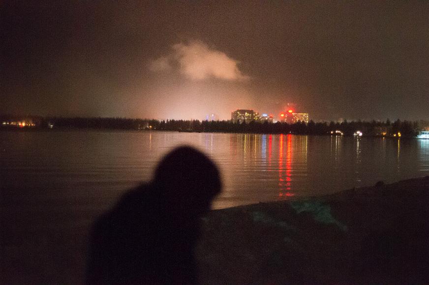 James in front the casinos over the nevada state line A man is blurred against a lake with casinos and one cloud lit up in the background in South Lake Tahoe California