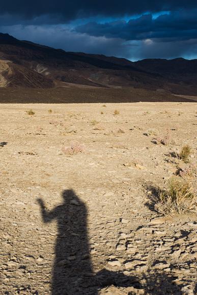 Me boxing my shadow just before sunset in the Saline Valley My shadow stretched across a barely vegetated valley in front of treeless mountains and dark and stormy blue grey clouds