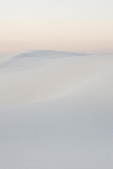 Some next level stuff White gypsum sand dunes geometrically dance underneath a pink and yellow usk sky in White Sands National Monument in New Mexico