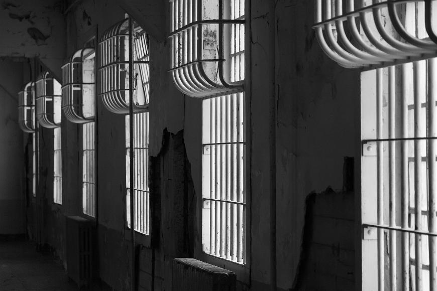 Windows with Bars on Alcatraz prisoner block Row of windows trailing off into the distance with a disintegrating wall and thick metal bars over every window